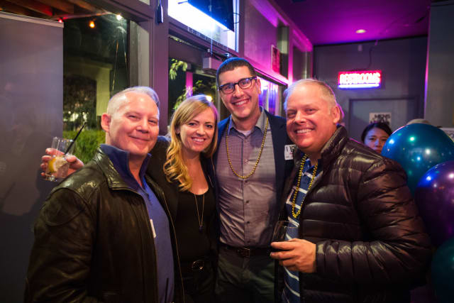 Group of four smiling individuals at the Love Bomb 2017 event, celebrating with drinks in a vibrant venue, showcasing community engagement and support for My Voice Music.